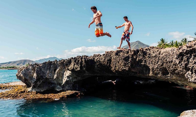 one man jumping off a cliff into the ocean on oahu